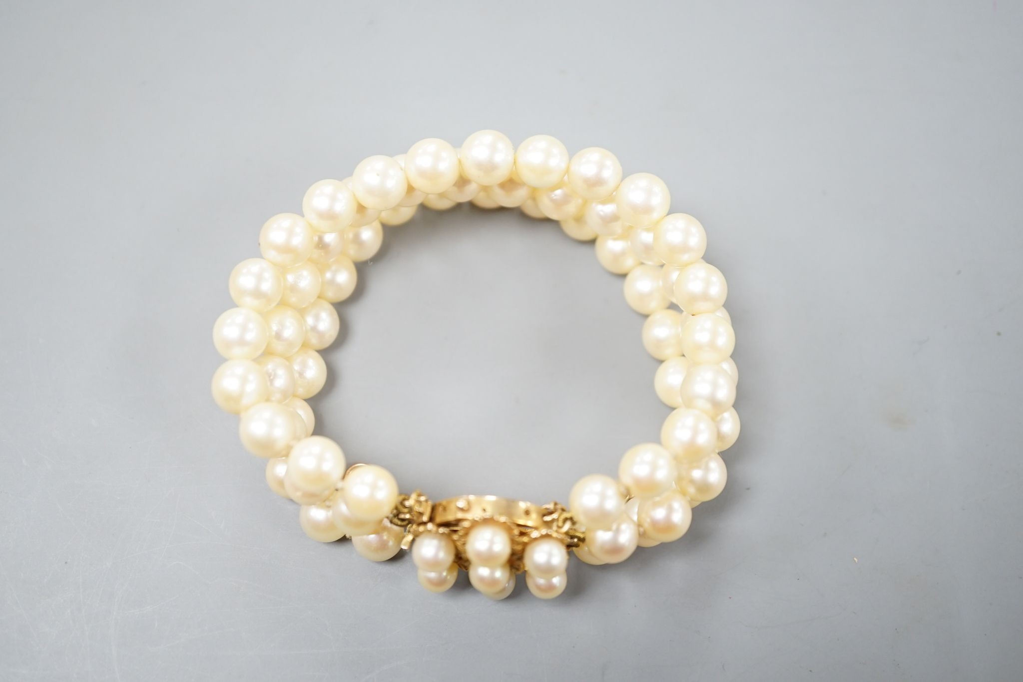 A triple strand cultured pearl bracelet, with yellow metal and cultured pearl cluster set clasp, approx. 16cm.